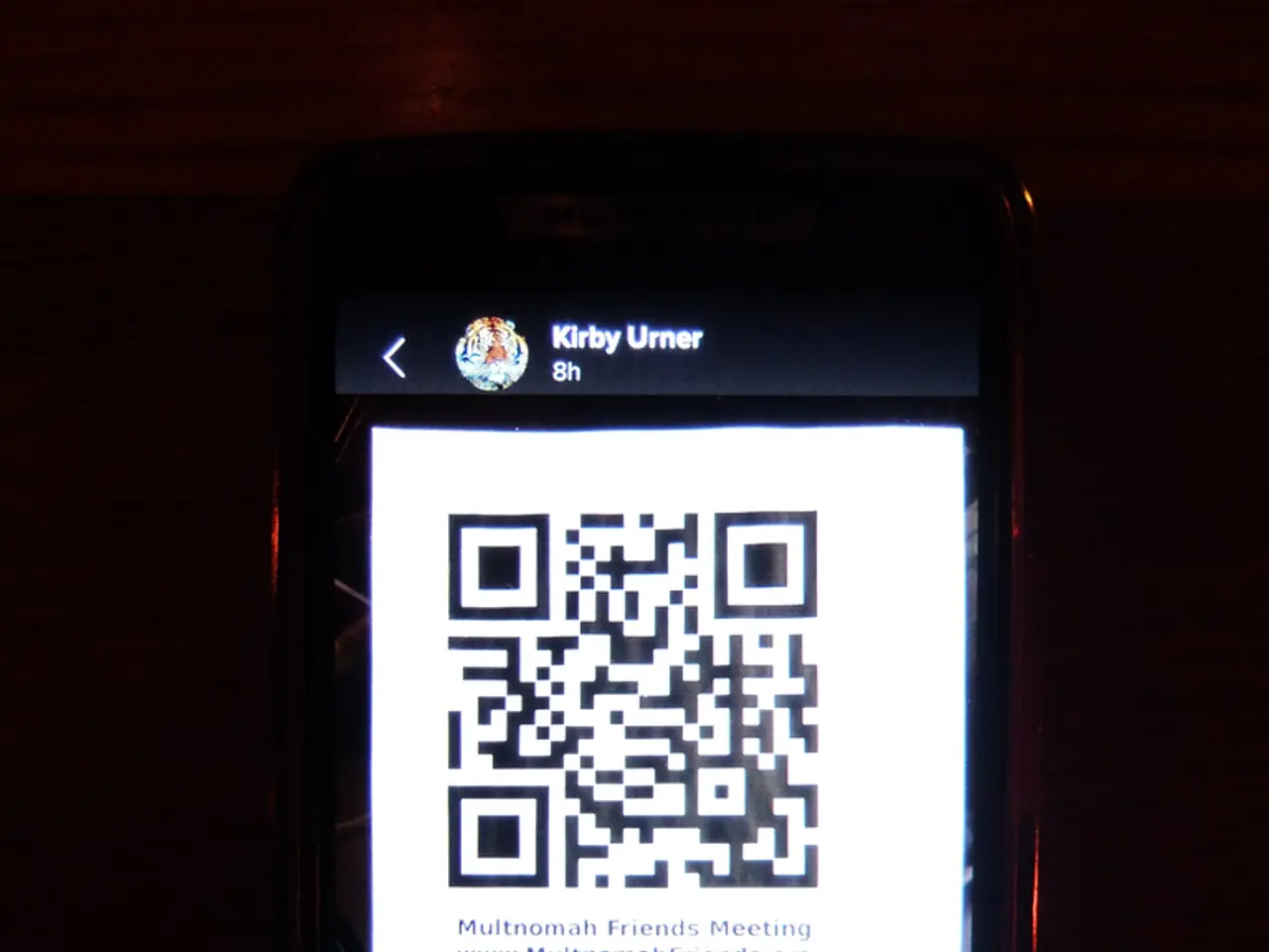 There is a mobile phone. There is a qr code on the screen.