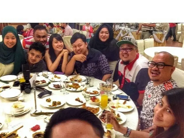 In this image I can see number of people are sitting here. I can also see smile on their faces....