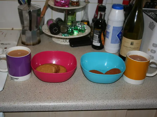 Here we can see a two cups and two bowls of biscuits. In the background we can see a wine bottle...