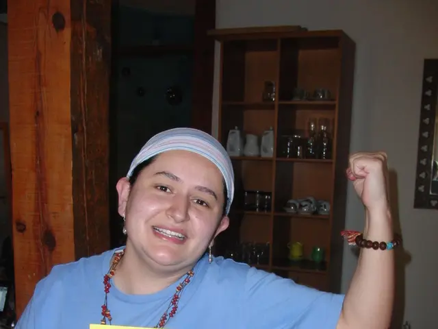 In the image I can see a person who is wearing the cap and holding the card and behind there are...