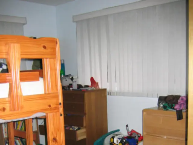 This is the picture of a room in which there is a double Decker bed, desk, table and some clothes...