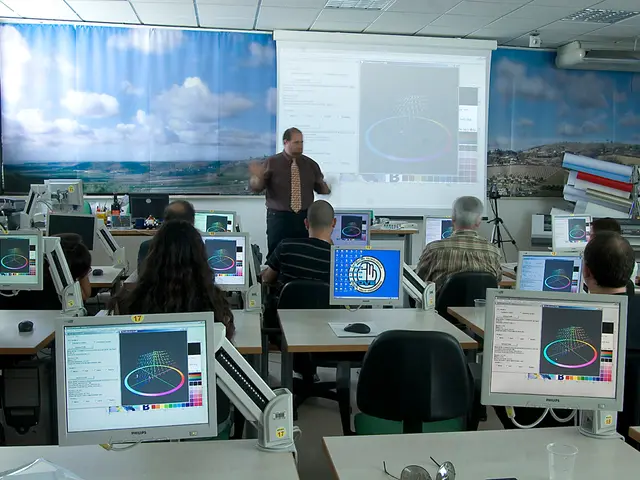 This picture there is a Man Standing and talking. Some of the people are sitting in front of a...