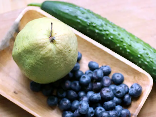 In this picture there is a wooden tray in the center of the image, which contains a guava and black...